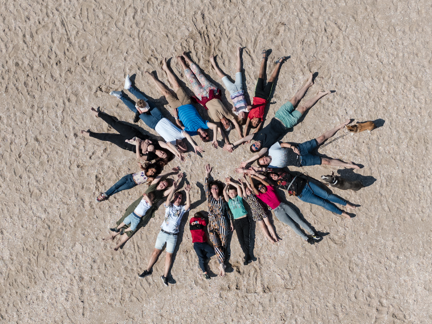 Groep mensen ligt in een cirkel op het strand, drone foto