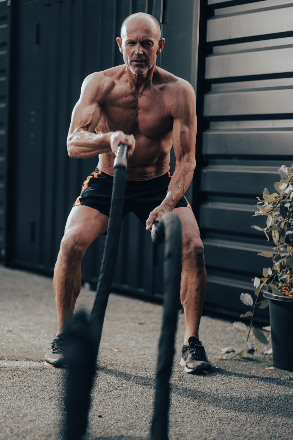Man traint met battle ropes tijdens een fitness fotoshoot